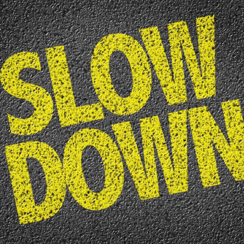 11 Tips To Negotiate Like A Pro: How To Close The Deal Image of the words slow down written on a road representing the need to not rush during a negotiation.