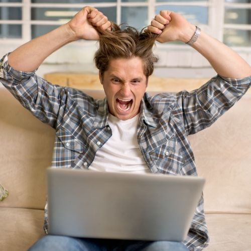 Image of a man pulling his hair with a laptop in front of him for failing technology section.