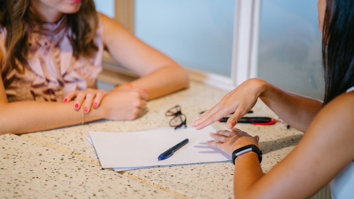 Two ladies sitting at a table coaching each other.