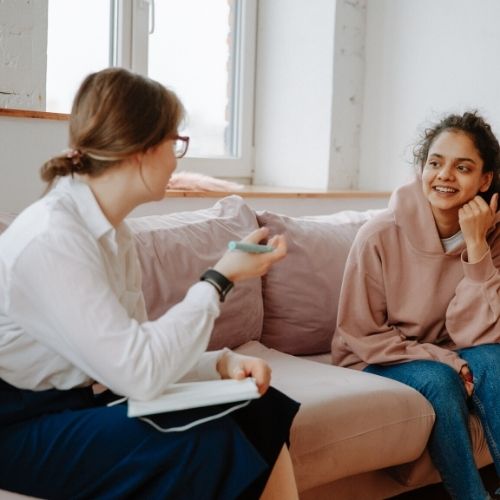 How To Find A Life Coach Online Today To Shatter Your Goals And Reach Astonishing New Heights Image of a person sitting on couch receiving advice from a life coach.