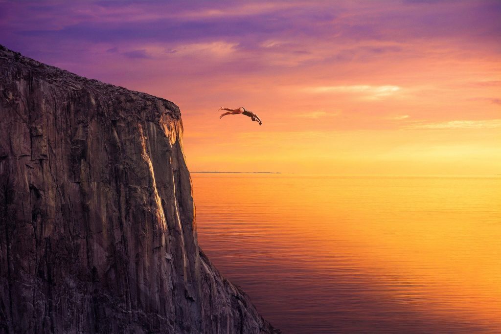 Image of a person jumping off a cliff representing the feeling when you step out of our comfort zone.