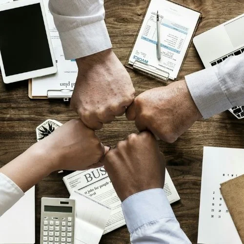 How to Run Effective Staff Meetings! 5 Easy Steps Image of four people fist-bumping after a successful meeting for tips on how to run effective staff meetings.