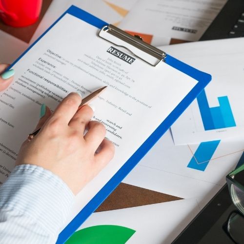 Interview Techniques for Employers to Find the Best Candidate Image of a person reviewing resumes for the post-interview process. The post-interview is one of the employer interview techniques.
