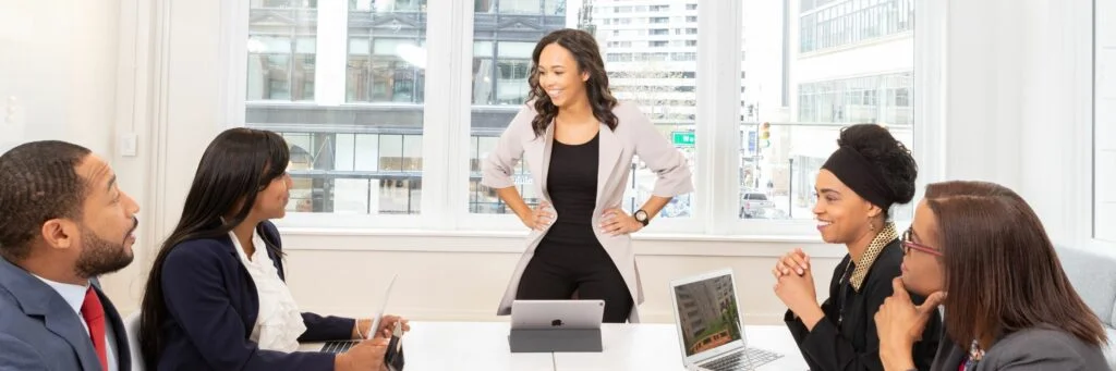 21 Expert Tips To Handle Disrespect In The Workplace Image of employees sitting around a table having a meeting. How to handle disrespect in the workplace.