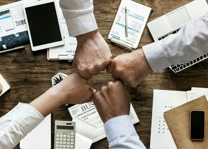 How to Build Strong Relationships at Work! 26 Tips Image of employees fist-bumping to build strong work relationships.