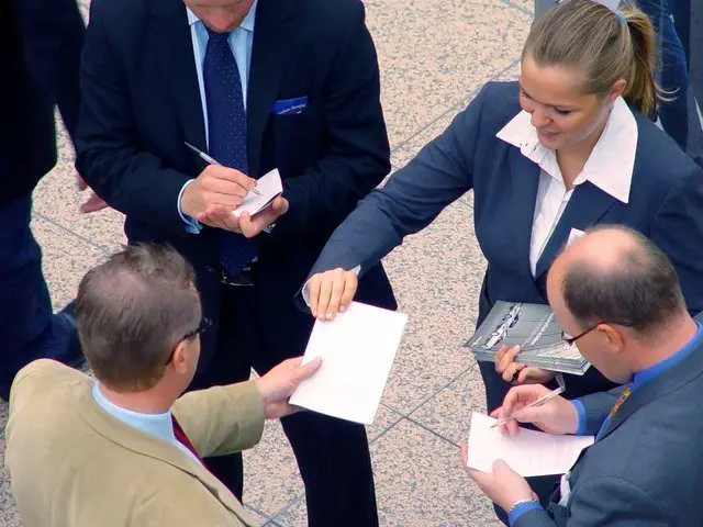 Image of a leader passing out leaflets to mentor showing how leaders coach others.