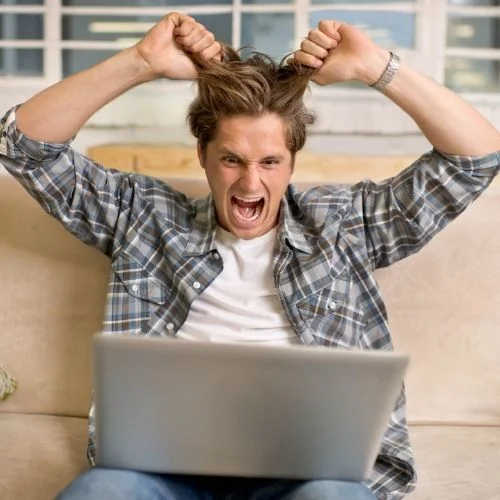 Image of a man pulling his hair with a laptop in front of him for failing technology section.