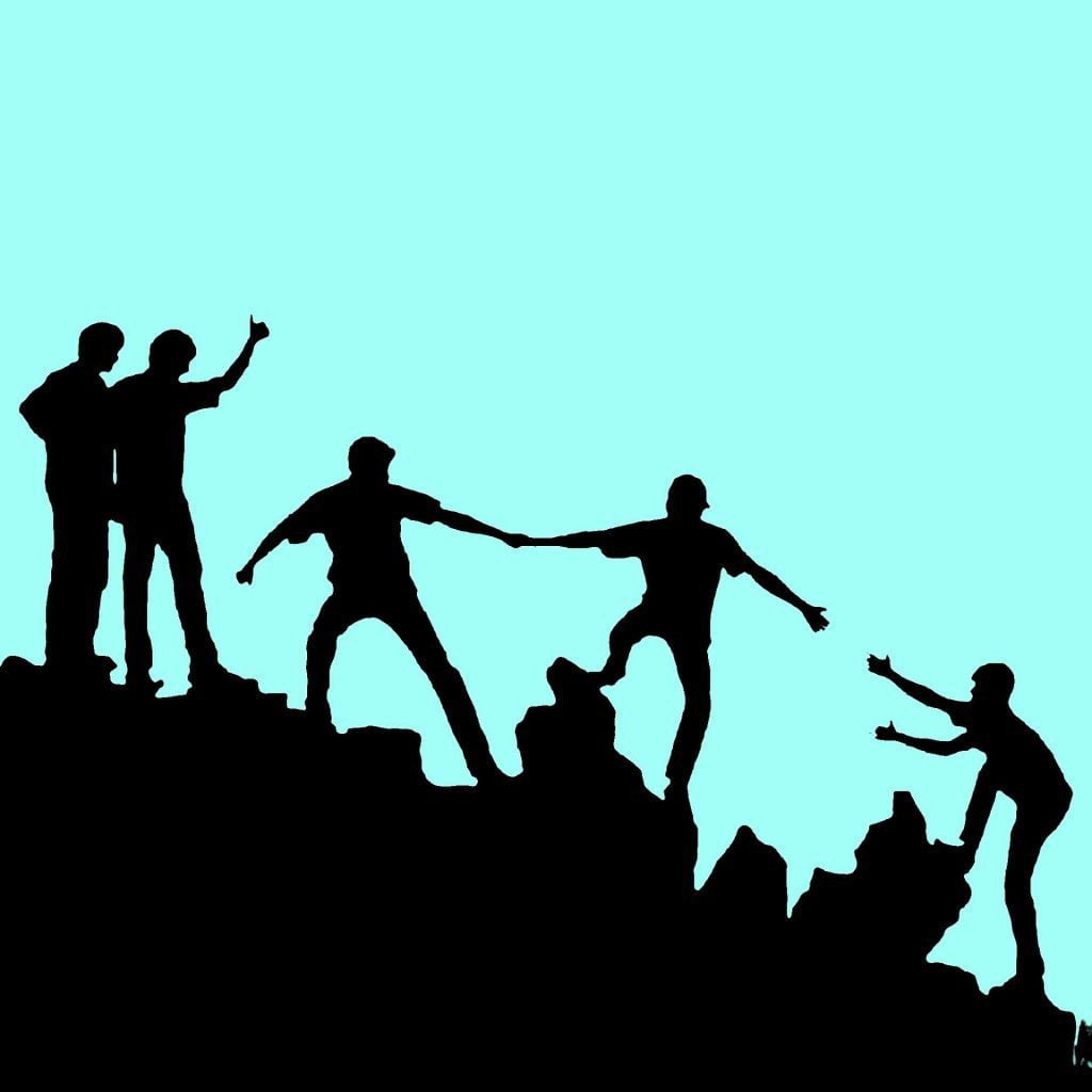 Image of people helping each other up a mountain representing the need for other people even while away from the office.