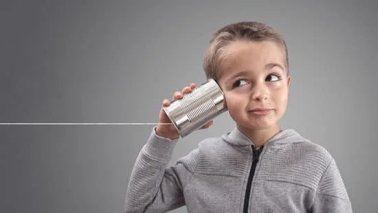How to Be a Good Communicator (24 Powerful Tips) Image of a boy listening into a can attached to a string to represent listening to improve communication skills, master communication skills.