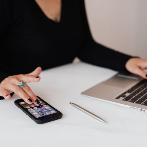 Image of a person using a smartphone and a laptop.