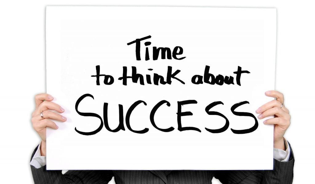 Image of a person holding a sign saying time to think about success for steps to create a vision statement section.