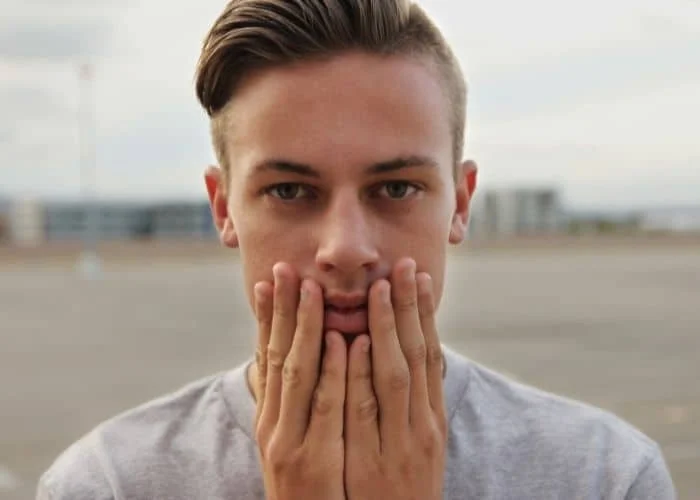 13 Body Language Examples: Understanding the Secrets A person touching their face.