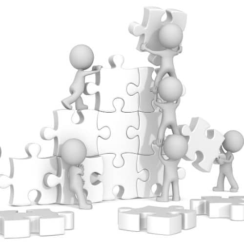 Image of workers putting puzzle pieces together representing team building games.