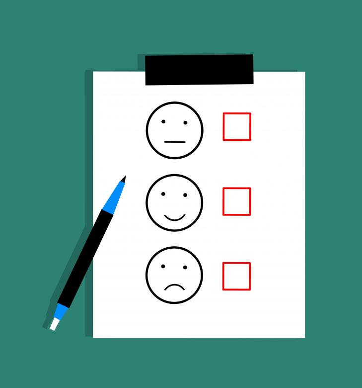 Piece of paper with happy, neutral, and frowned faces with checkmarks next to them to represent feedback.