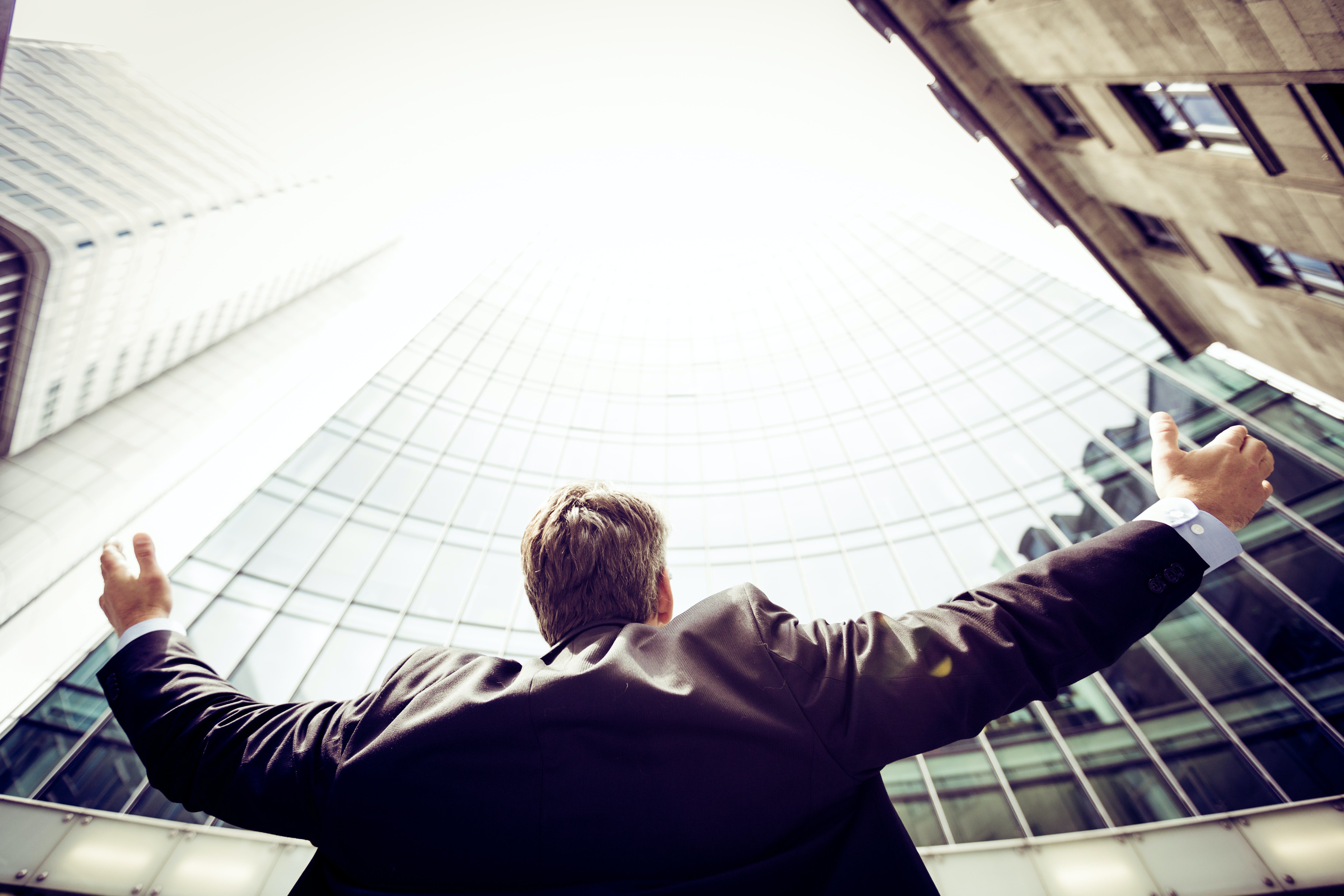 how to empower others. Business man looking up at buildings.