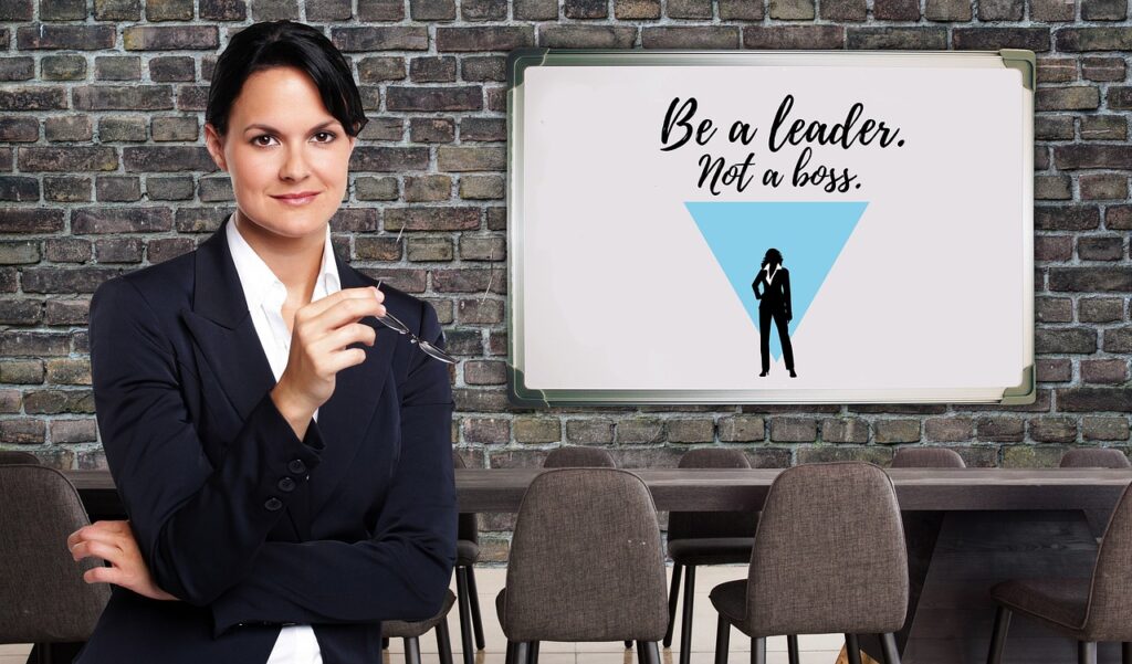 Discover The 12 Essential Qualities Of A Good Leader A business woman with a white board that says be a leader not a boss displaying one of the 12 qualities of a good leader.