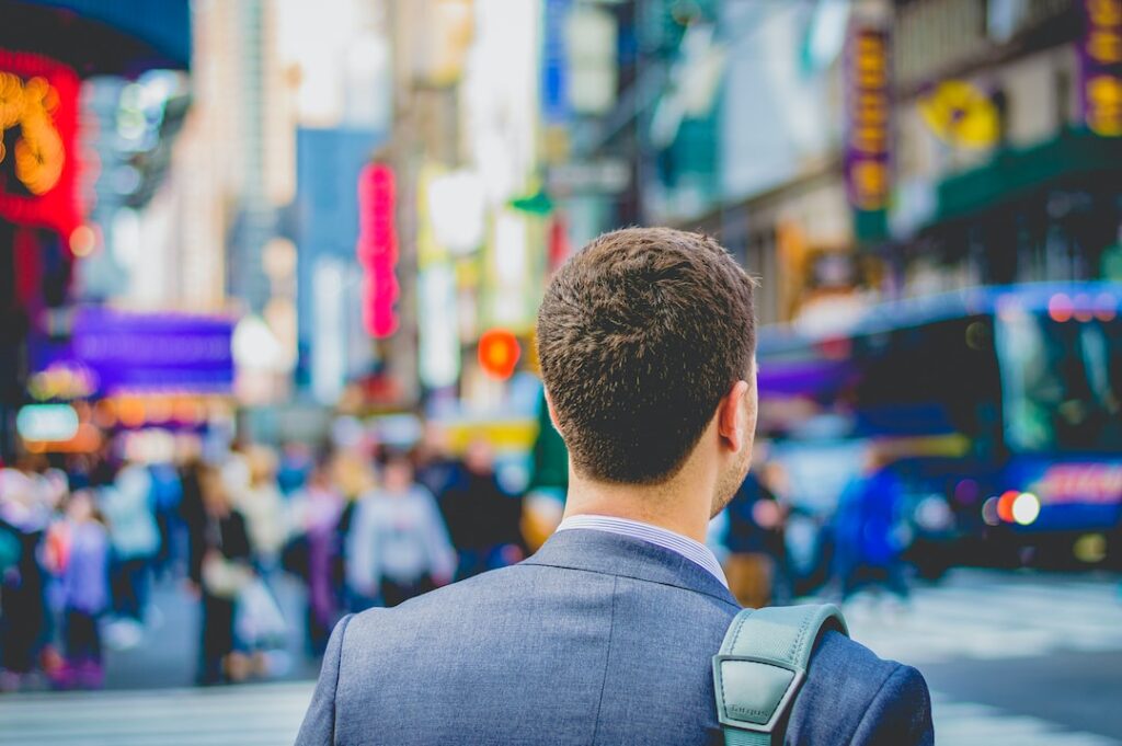 Job vs Career: Punching the Clock or Pursuing Your Passion Man in a suit looking at a busy street ready to embark on journey of a career vs job.