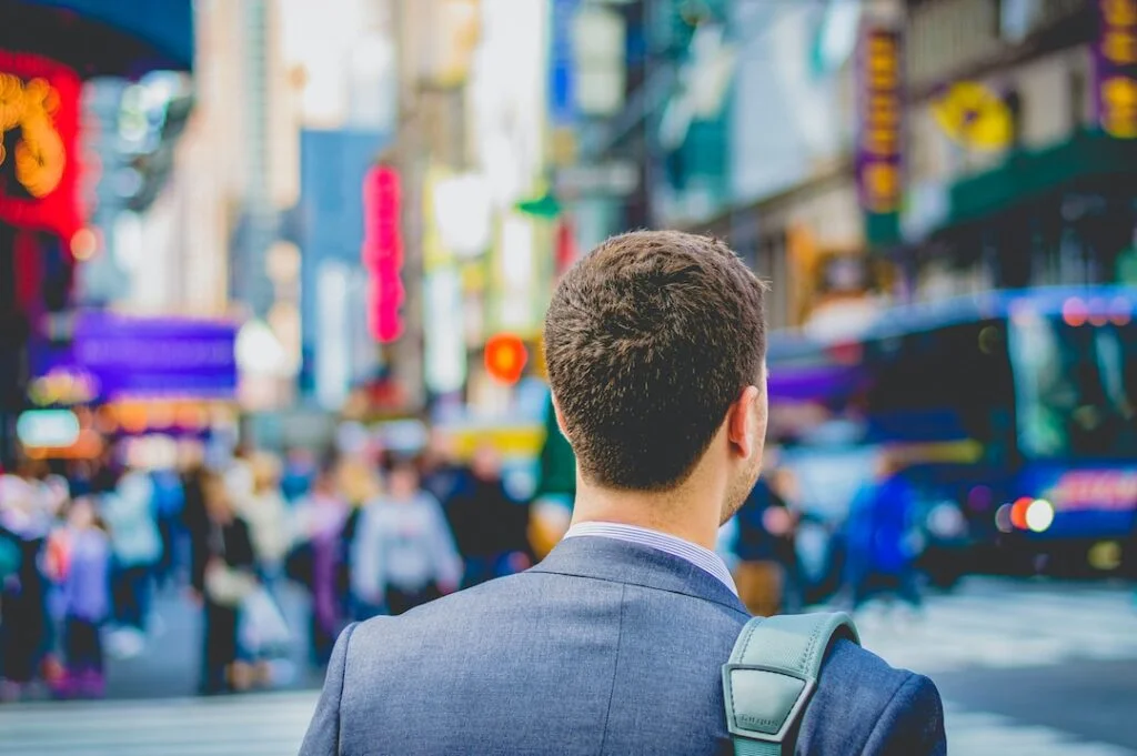 Job vs Career: Punching the Clock or Pursuing Your Passion Man in a suit looking at a busy street ready to embark on journey of a career vs job.
