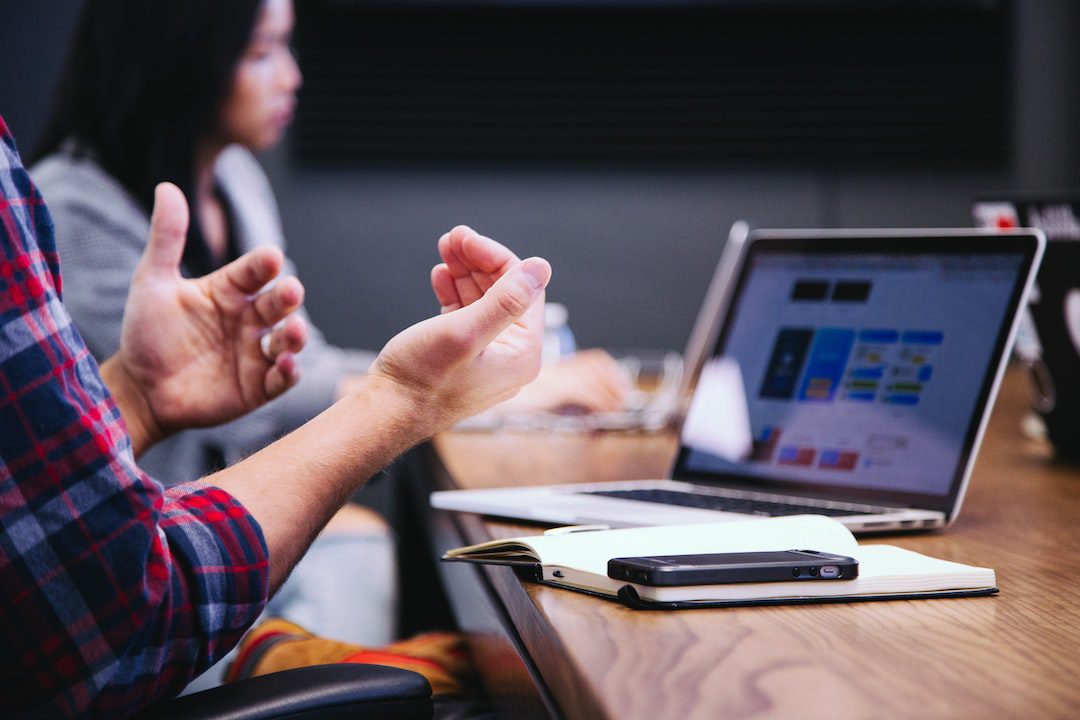 36 Crucial Tips for Improving Communication in the Workplace Person on laptop gesturing with his hands while talking showing the use of non verbal communication in the workplace.