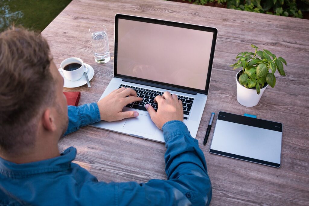 Hybrid Work Model Best Practices to Dominate Work-Life Balance Man working on a laptop in a hybrid workplace.