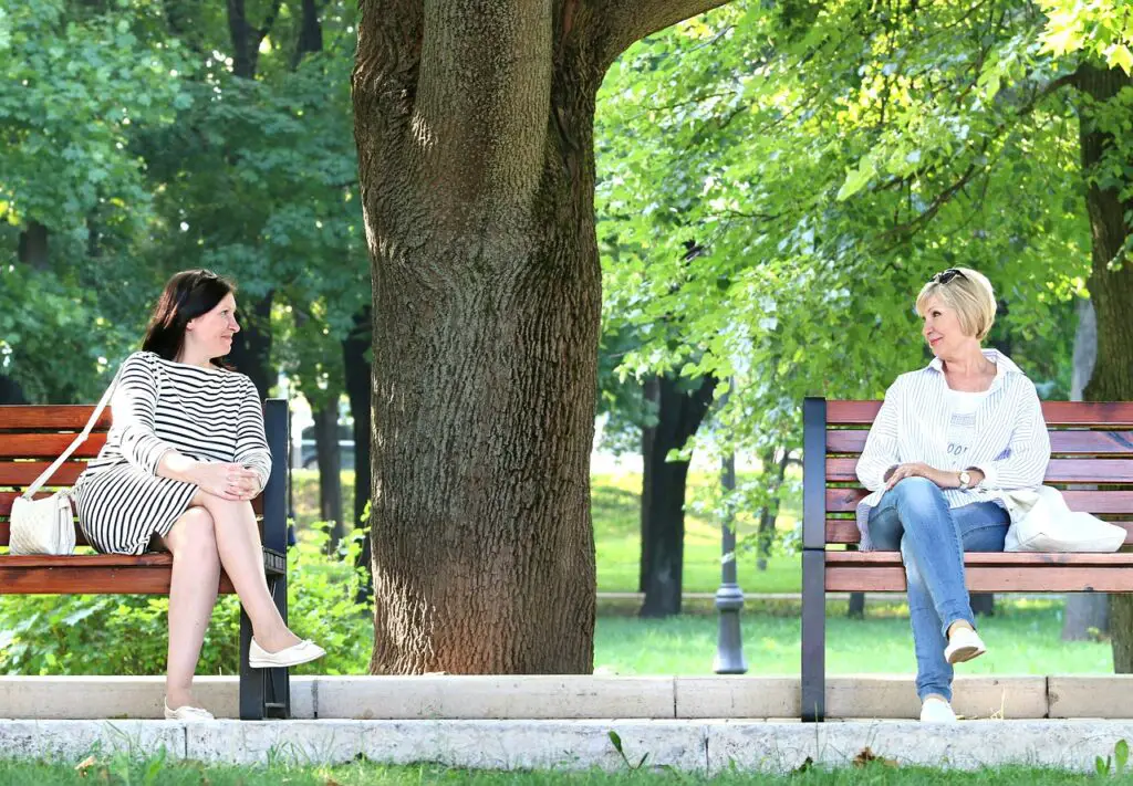Two women on benches using small talk, the first of five levels of communication.